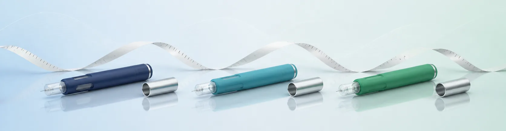 Weight loss injections shown as three subcutaneous injector pens with a measuring tape backdrop